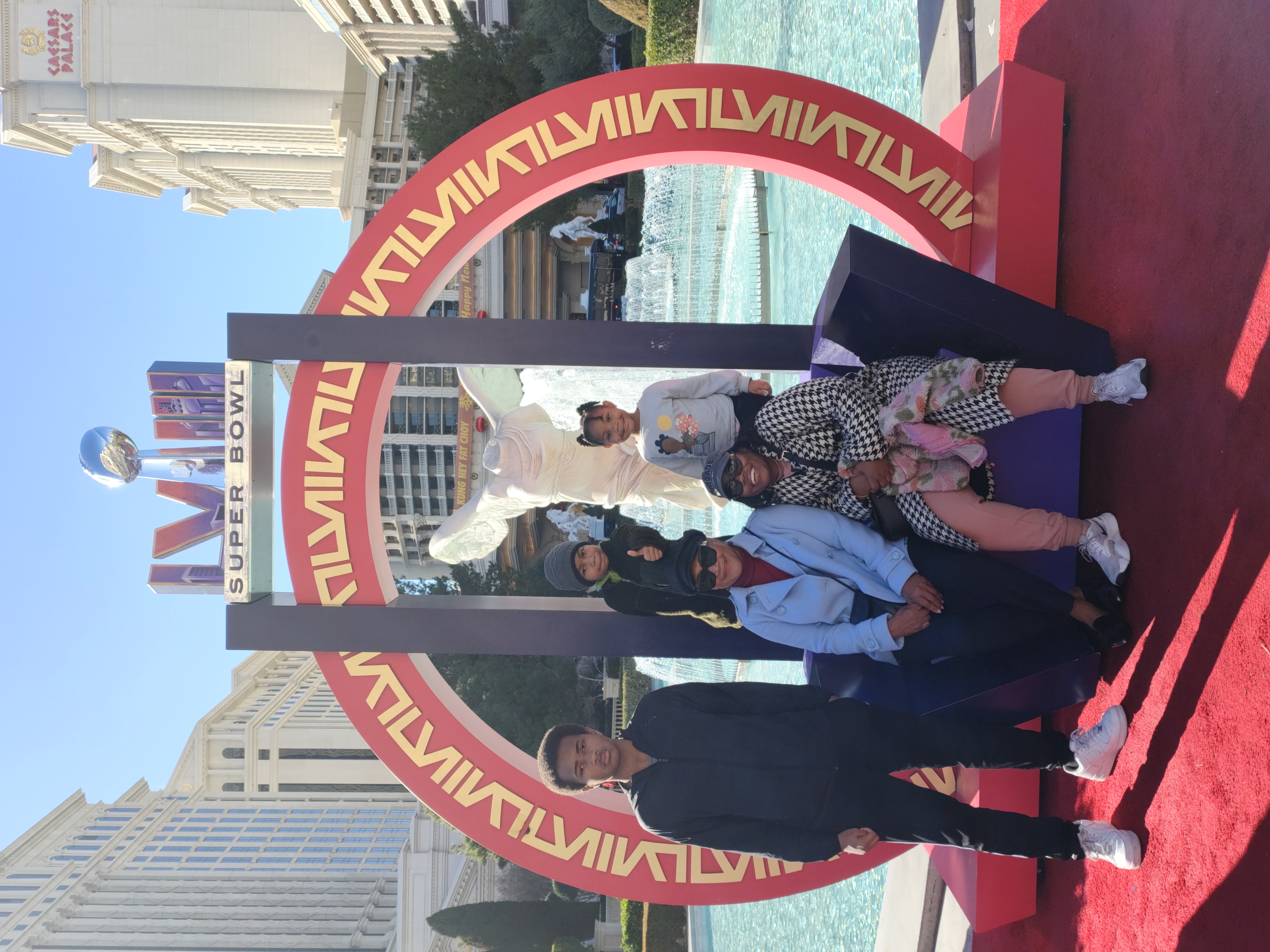 Arielle Rollins Family sitting outside by a fountain for a family photo.