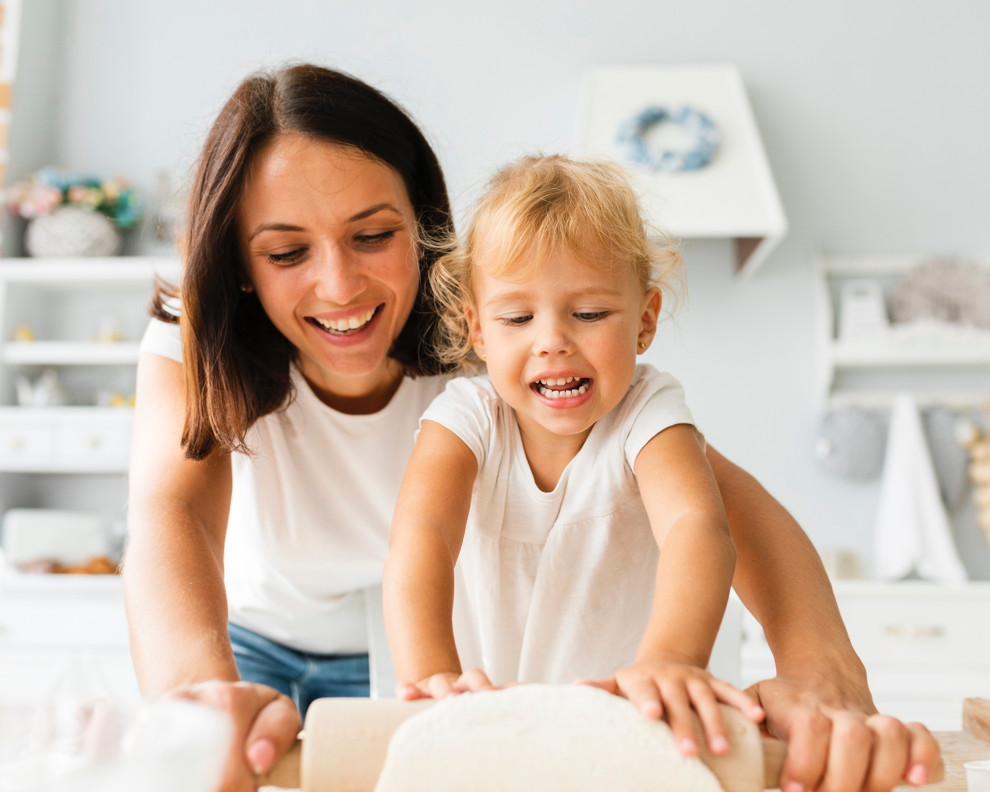 Adult female and toddler in a bright at home setting smiling.