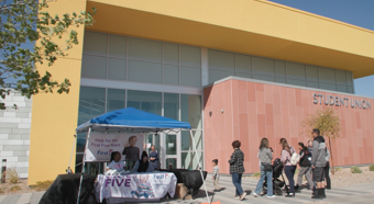 Exterior shot of a Student Union building with First 5 Nevada booth set up outside. People walking in to the event. 