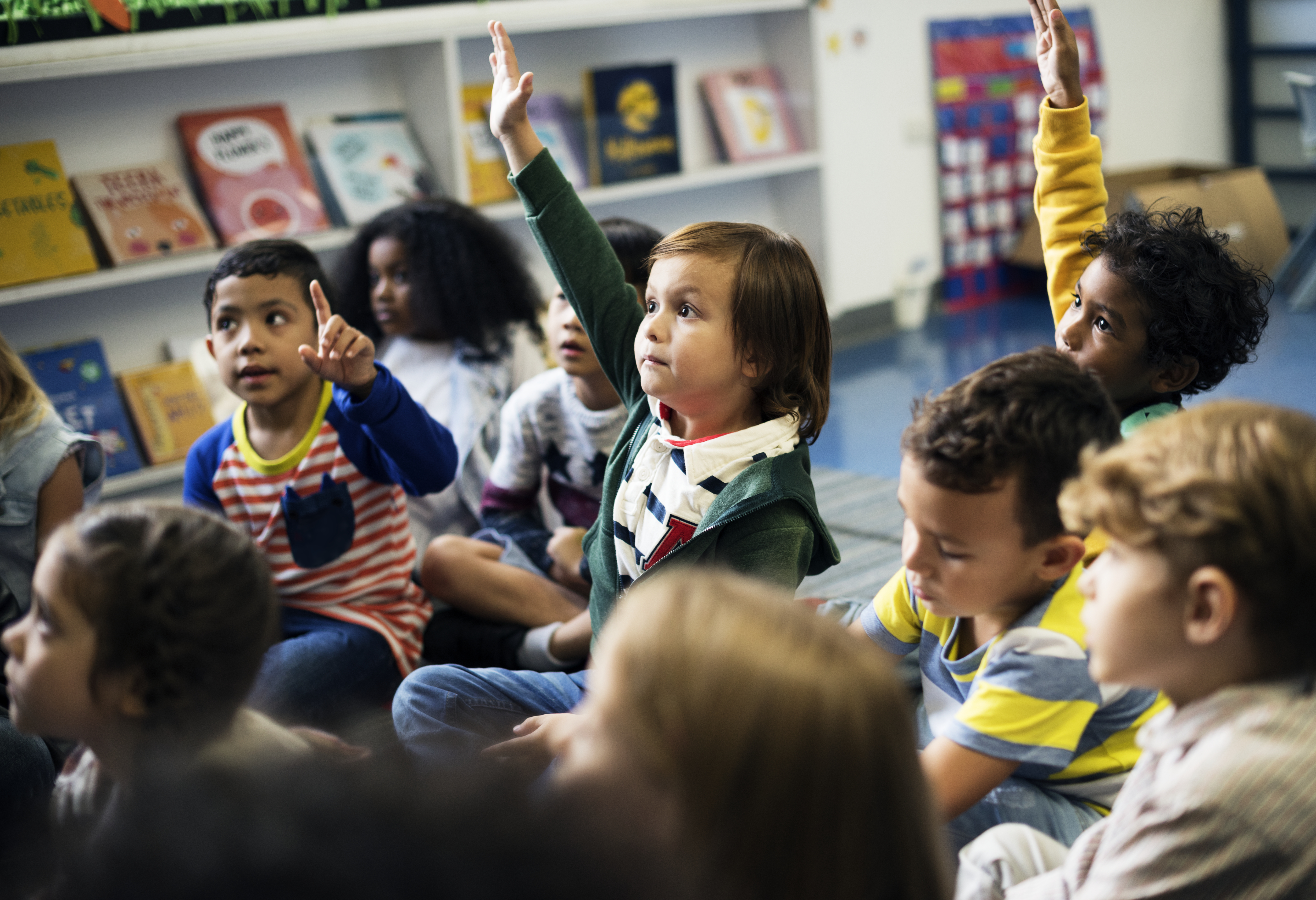 A group of children sitting on the floor in a classroom.