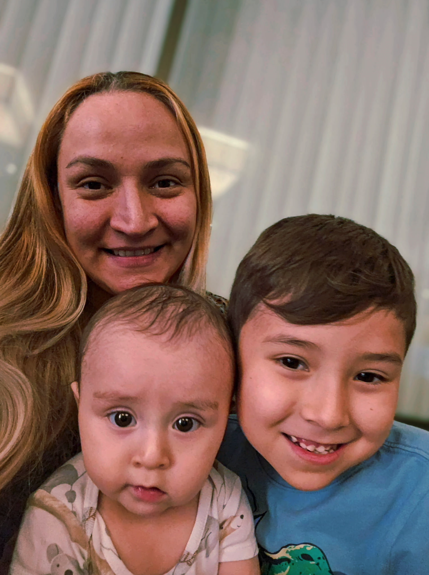 Adult female and two young toddlers smiling at camera posting for photo