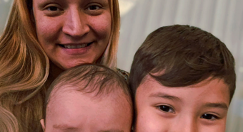 Adult female and two young toddlers smiling at camera posting for photo