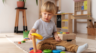 Little boy sits on floor, playing with colorful block toys