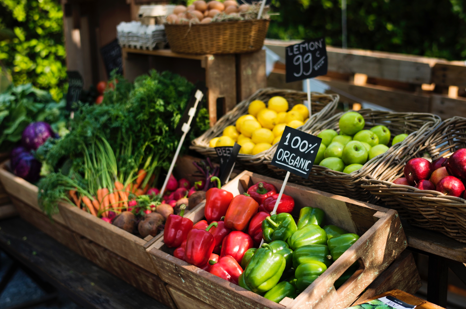 Fruits and vegetables in a farmers market setting. Bell peppers, carrots, lemons and apples in little baskets. 