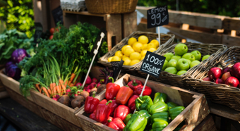 Fruits and vegetables in a farmers market setting. Bell peppers, carrots, lemons and apples in little baskets. 