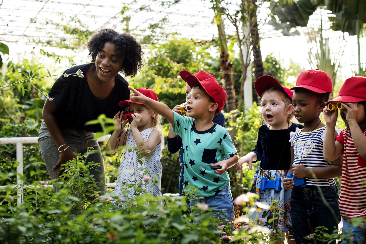 Group of young students and a teacher looking at flowers.