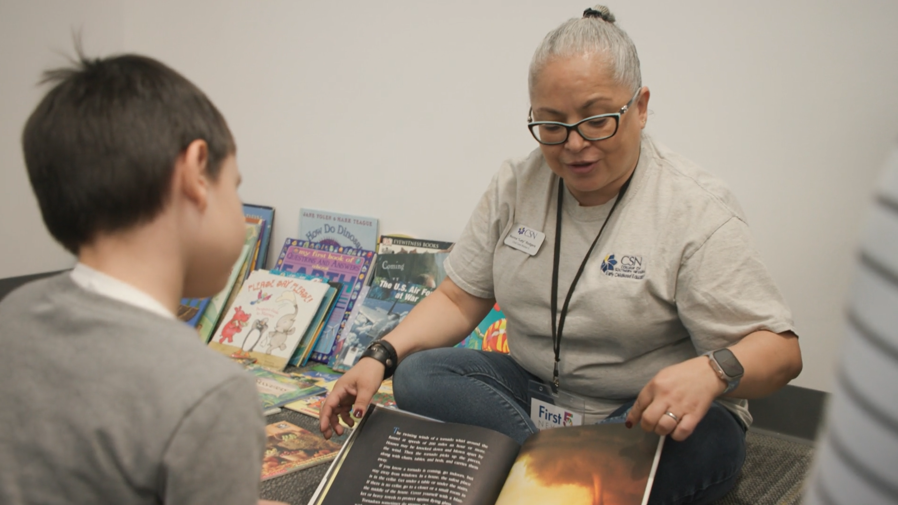 Women and kid sitting on floor while women reads a story to the child. 