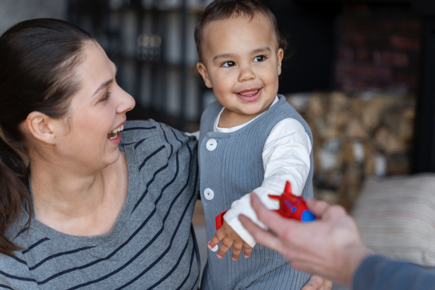 Adult female holding smiling toddler.