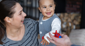 Adult female holding smiling toddler.