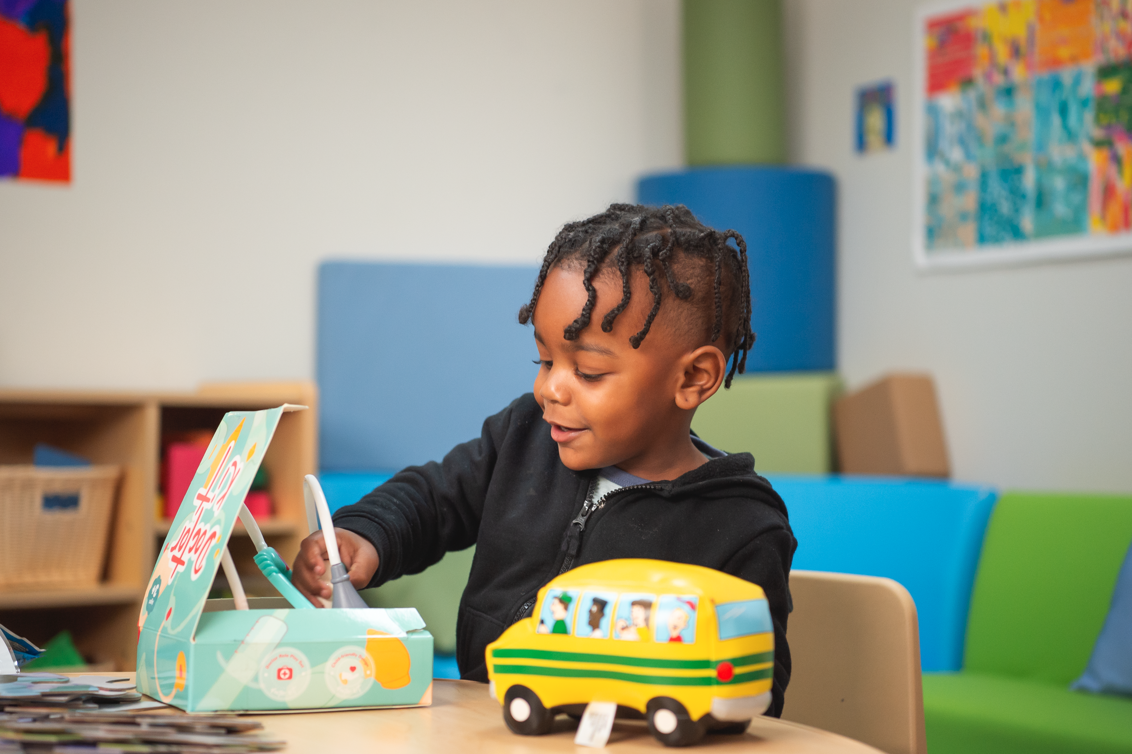 Young boy playing with toys while sitting at a desk in a fun classroom setting.