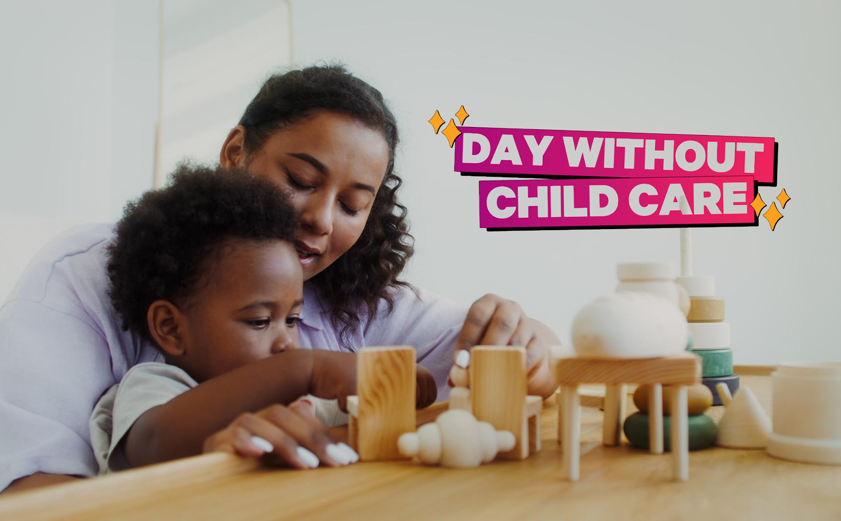 Childcare taker sits with toddler at a table while the little boy plays with toy blocks on the table. 