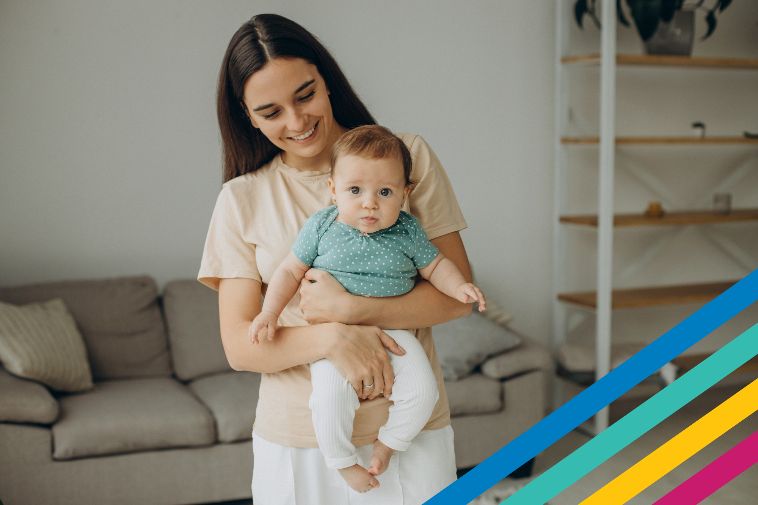 Adult female holding toddler in her arms looking at the toddler and smiling. In a comfy house setting. 