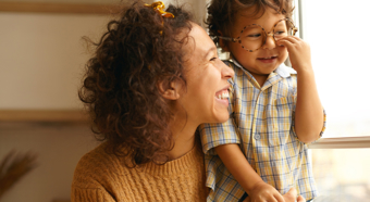 Adult female smiling at toddler in her lap. In a cozy home setting.