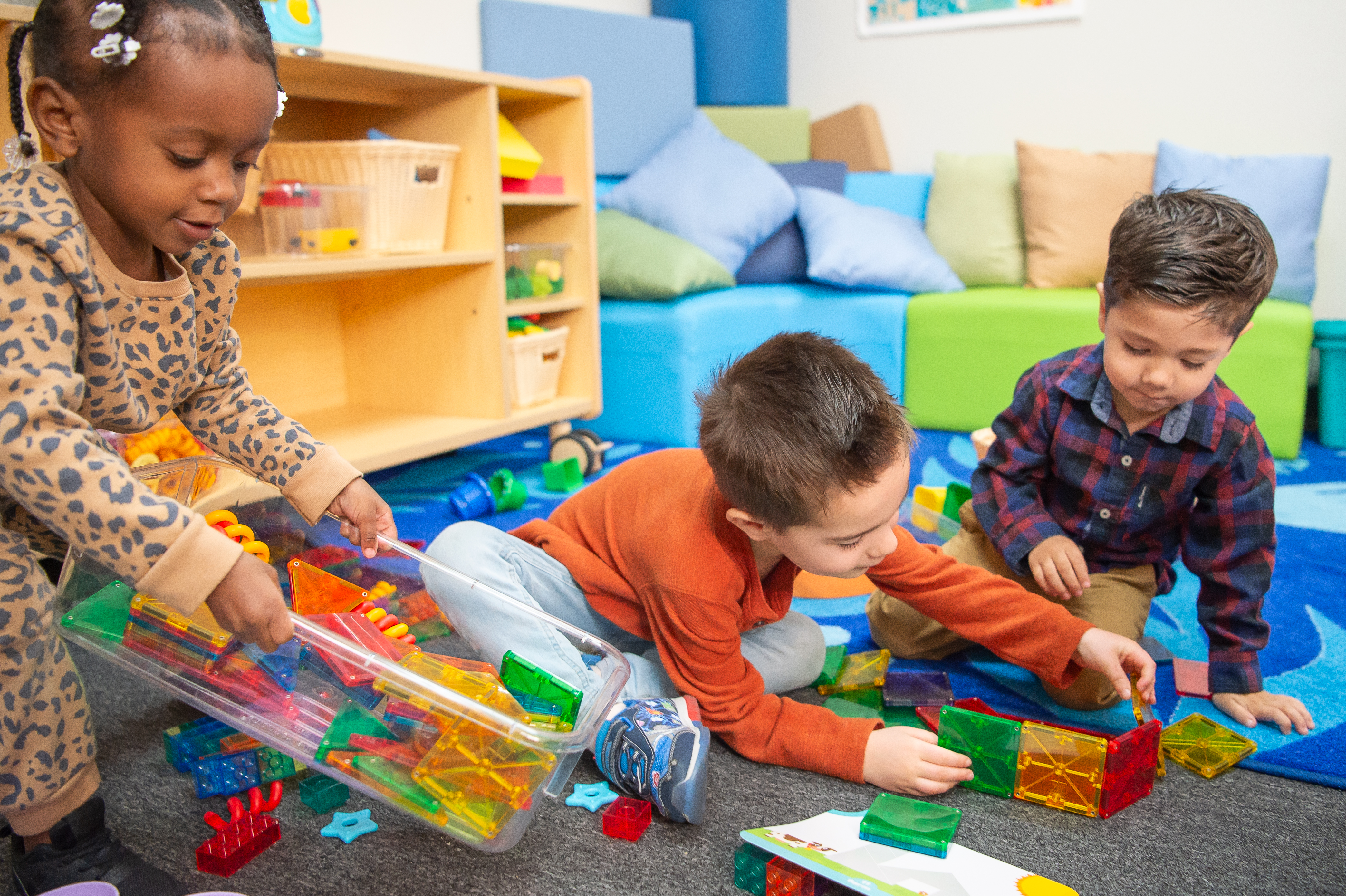 Three young children playing with blocks on the floor.