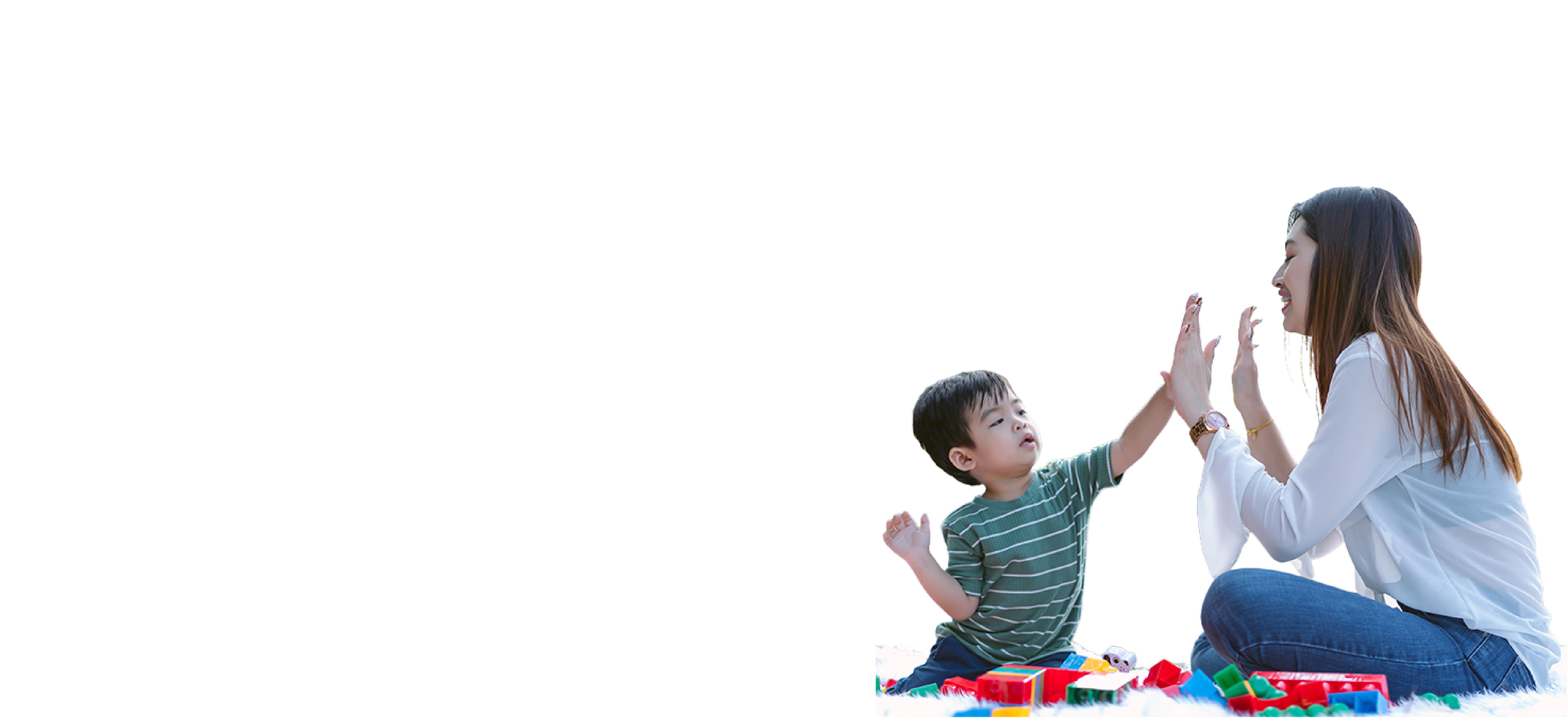 Young light-skinned, dark-haired boy with a green shirt with light stripes, high fiving a light-skinned, brown-haired woman wearing a white shirt and jeans, with colorful toy building blocks around.