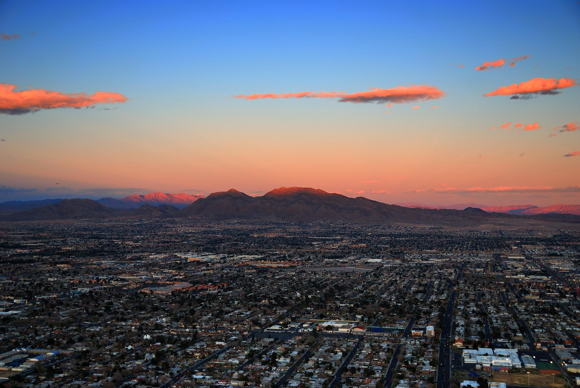 Aerial shot of Nevada skyline during sunset, mountains in background and city buildings in front 