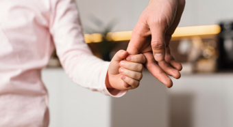 Closeup shot showing a hand of a small child holding hand of an adult.