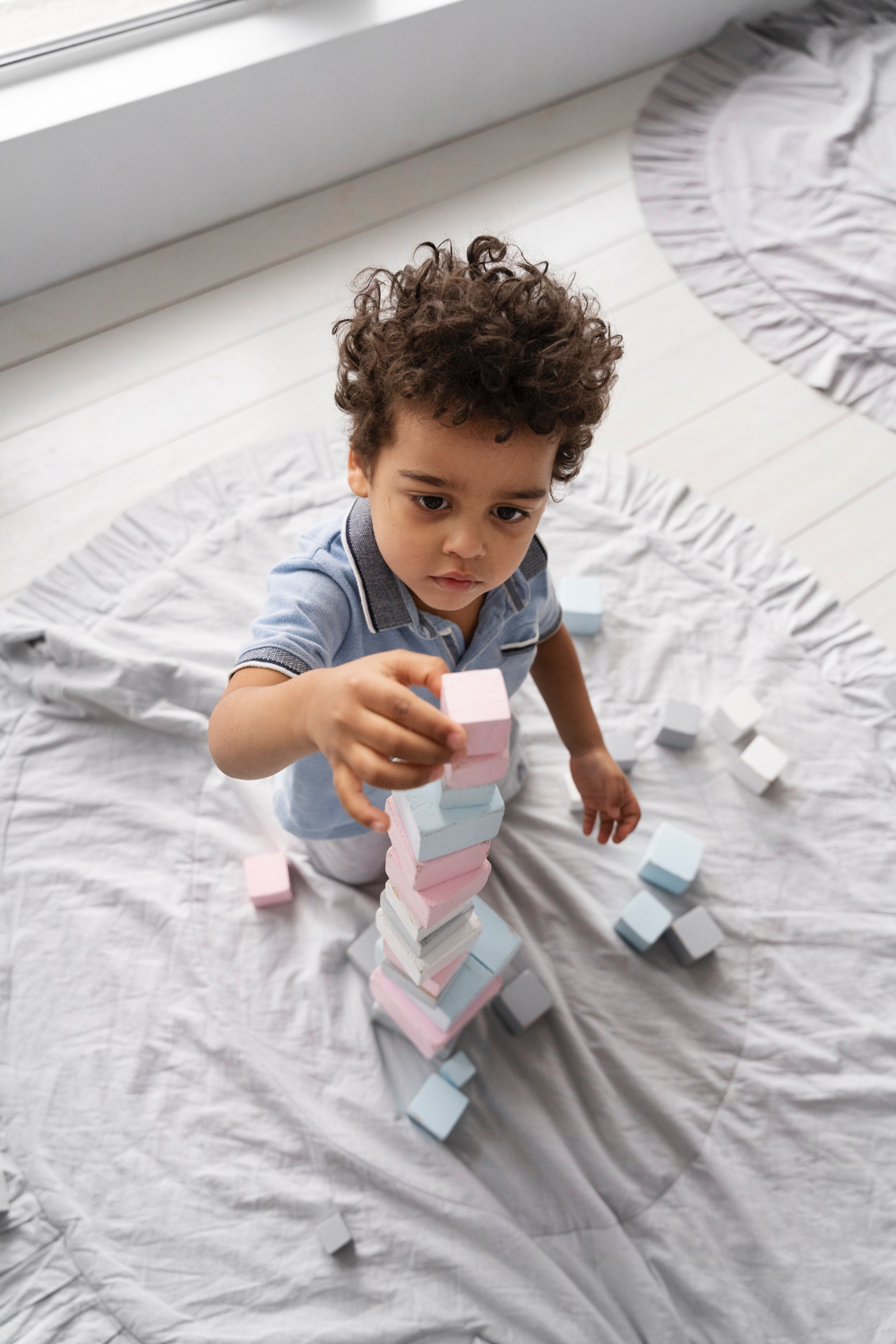 Closeup of toddler kid stacking little blocks in comfy at home setting.