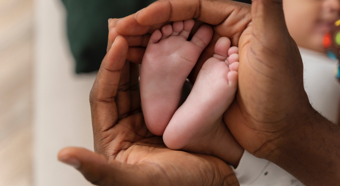 Closeup of a baby's feet, with adult hands holding the feet. 